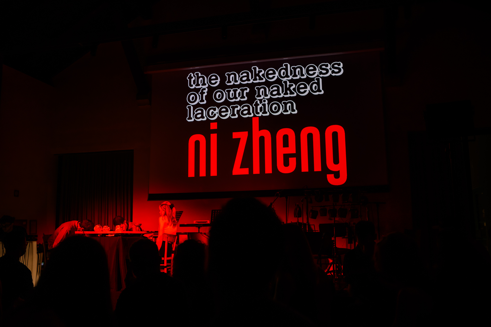 Index Ensemble performing under red stage lighting, with a projection for Ni Zheng’s work behind the musicians.
