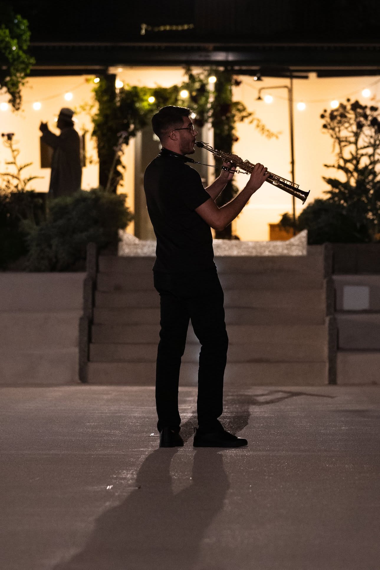 Alberto Cavallaro playing soprano saxophone outdoors in the evening.